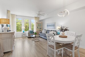 Ein modernes Wohnzimmer mit Essbereich, Deckenventilator und großen Fenstern.