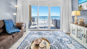 Ein Wohnzimmer mit Blick auf den Strand, inklusive Sofa, Couchtisch und Lampe.