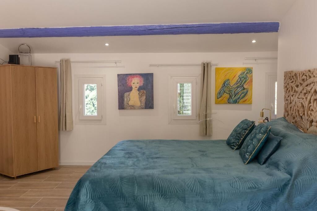 A bedroom with a large bed, a wardrobe, and artwork on the walls.
