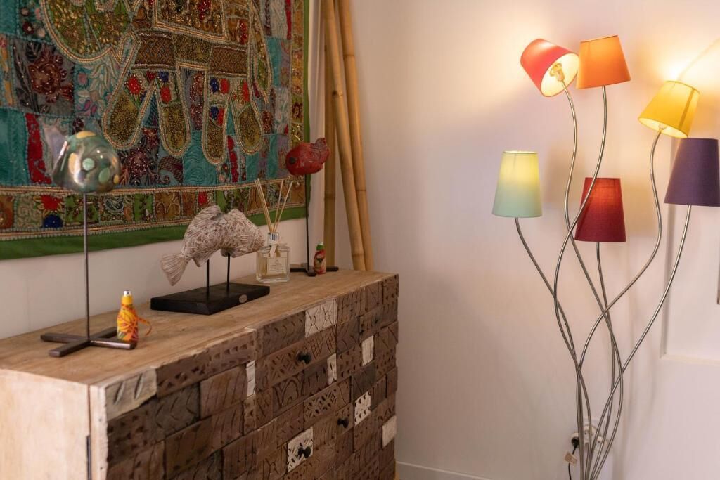 A room with a decorative wall hanging, a wooden cabinet with drawers, and a floor lamp with multiple lamps.