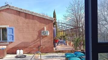 Ein Poolbereich mit einer Steindeck, ein Haus mit roter Fassade und Gartenmöbeln.