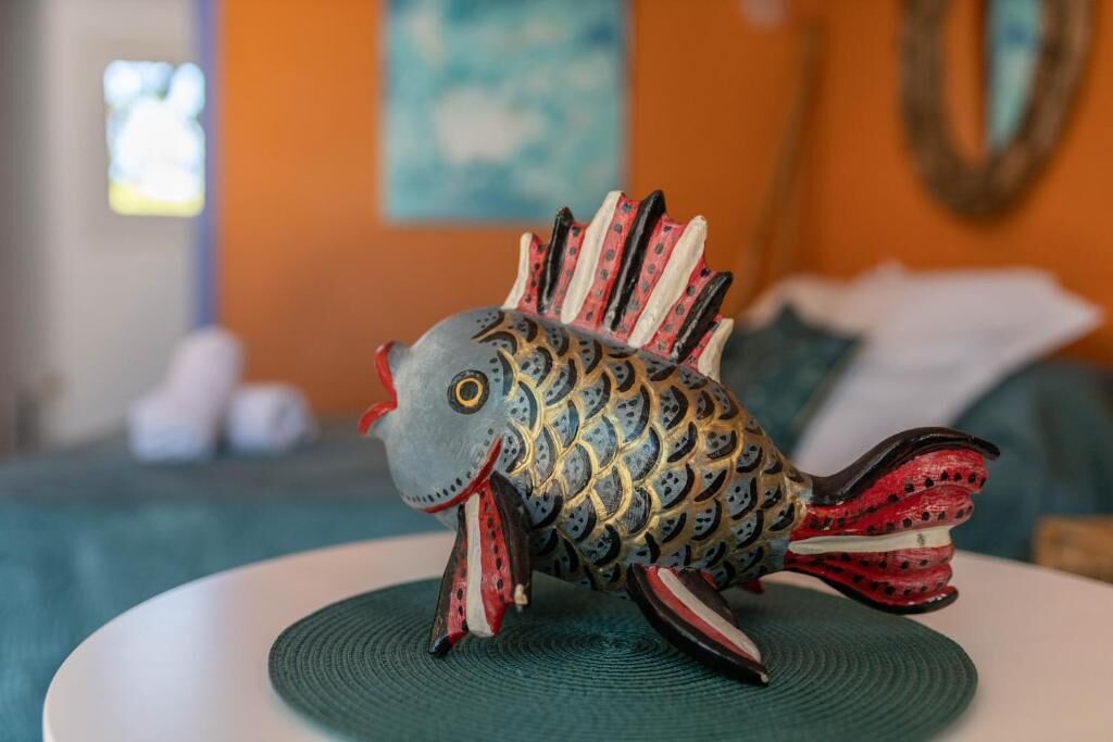 A decorative fish sculpture on a round table in a room with a couch and a painting on the wall.