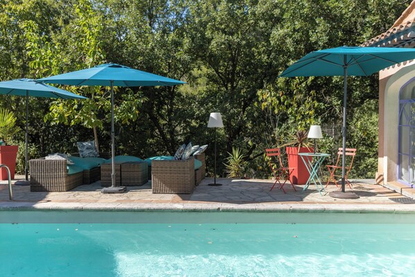 A poolside area with wicker furniture, umbrellas, and a small table with chairs. - Casa AMMIRATI Flayosc (Flayosc)