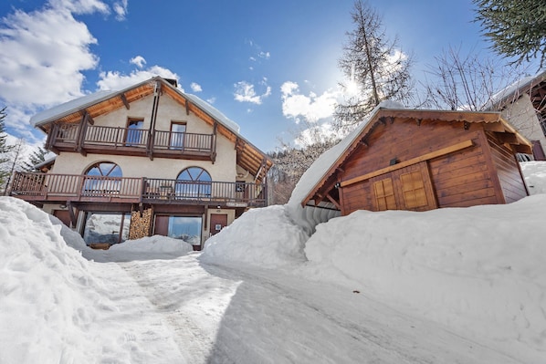 A chalet-style building with a balcony, large windows, and a wooden facade.