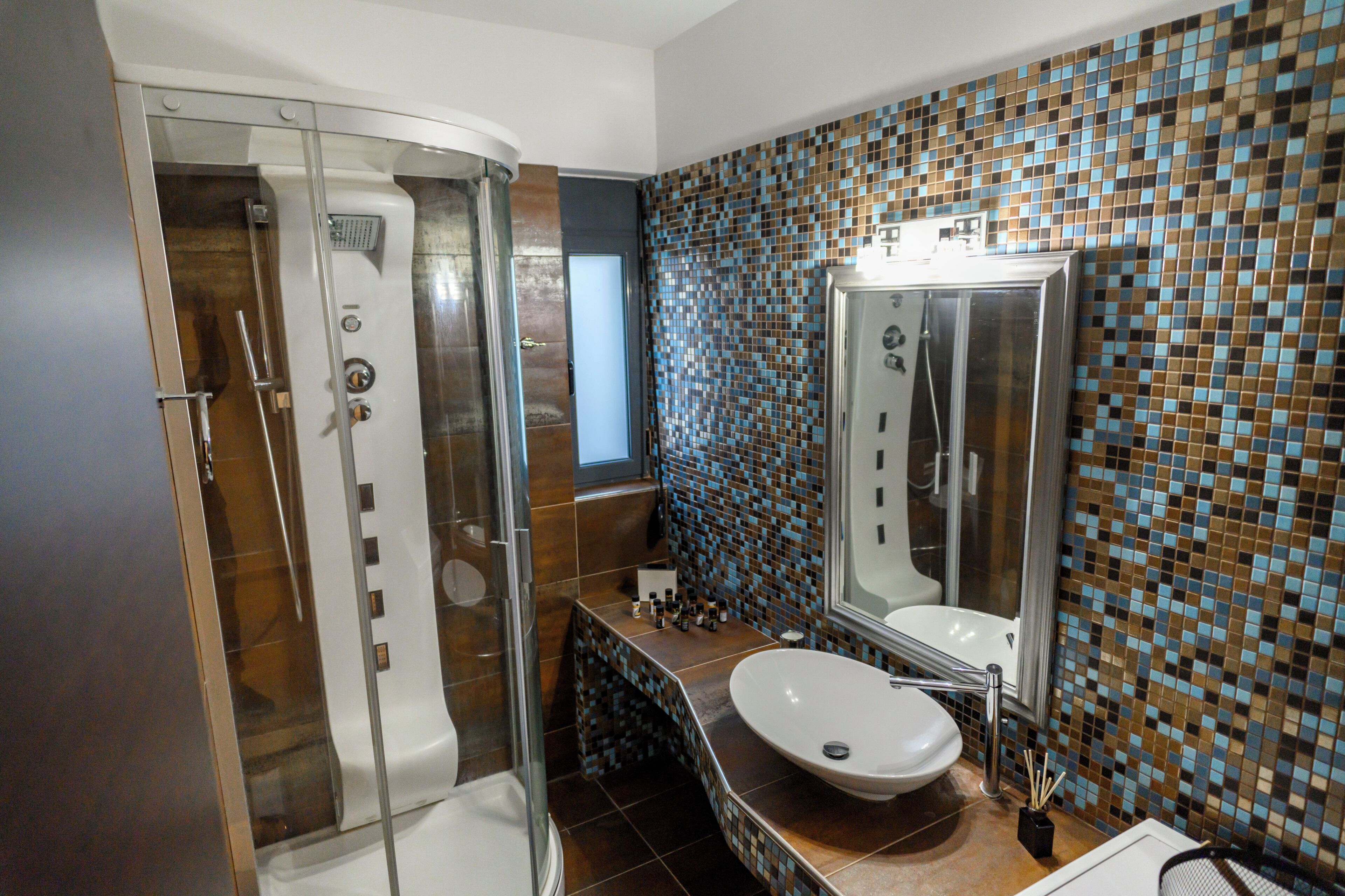 Une salle de bain avec une douche à parois de verre, un lavabo avec un miroir et un mur recouvert de carreaux.