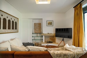 Una sala de estar con sofá, televisor de pantalla plana, chimenea y un cuadro colgado en la pared.