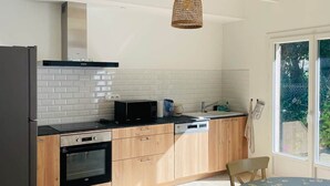 Una cocina moderna con baldosas blancas, armarios de madera, un horno negro y un comedor con mesa y sillas.