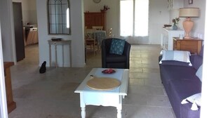 Amplia sala de estar con una mesa de comedor, un sofá, una silla y una cocina al fondo.
