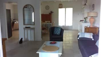 A spacious living area with a dining table, a sofa, a chair, and a kitchen in the background.