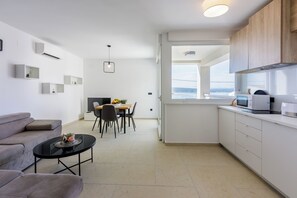 Ein moderner, minimalistischer Wohn- und Essbereich mit einer Couch, Esstisch und Küchenzeile.