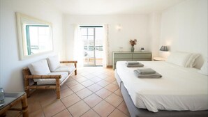 Una camera d'albergo con un letto, un divano, una cassettiera e un balcone.