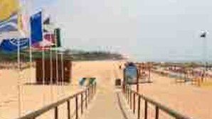 A boardwalk leading to a beach area with a lifeguard tower and flags. - Delgado Alves Apartment (Quarteira)