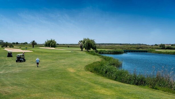 A golf course with a water body, a bridge, and a clear sky. - Delgado Alves Apartment (Quarteira)