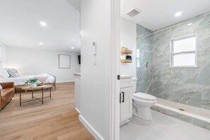 Ein modernes Badezimmer mit einer gläsernen Duschkabine, einer weißen Toilette und einer Marmorablage.