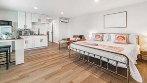 A modern bedroom with a bed, bedside table, and a small desk area with a chair.