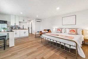 A modern bedroom with a bed, bedside table, and a small desk area with a chair. - I Unbeatable location I Sun & Salt Studio I (Jacksonville Beach)
