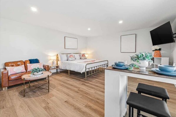 Ein modernes, kompaktes Wohnzimmer mit Bett, Sofa, Essbereich und Küche.