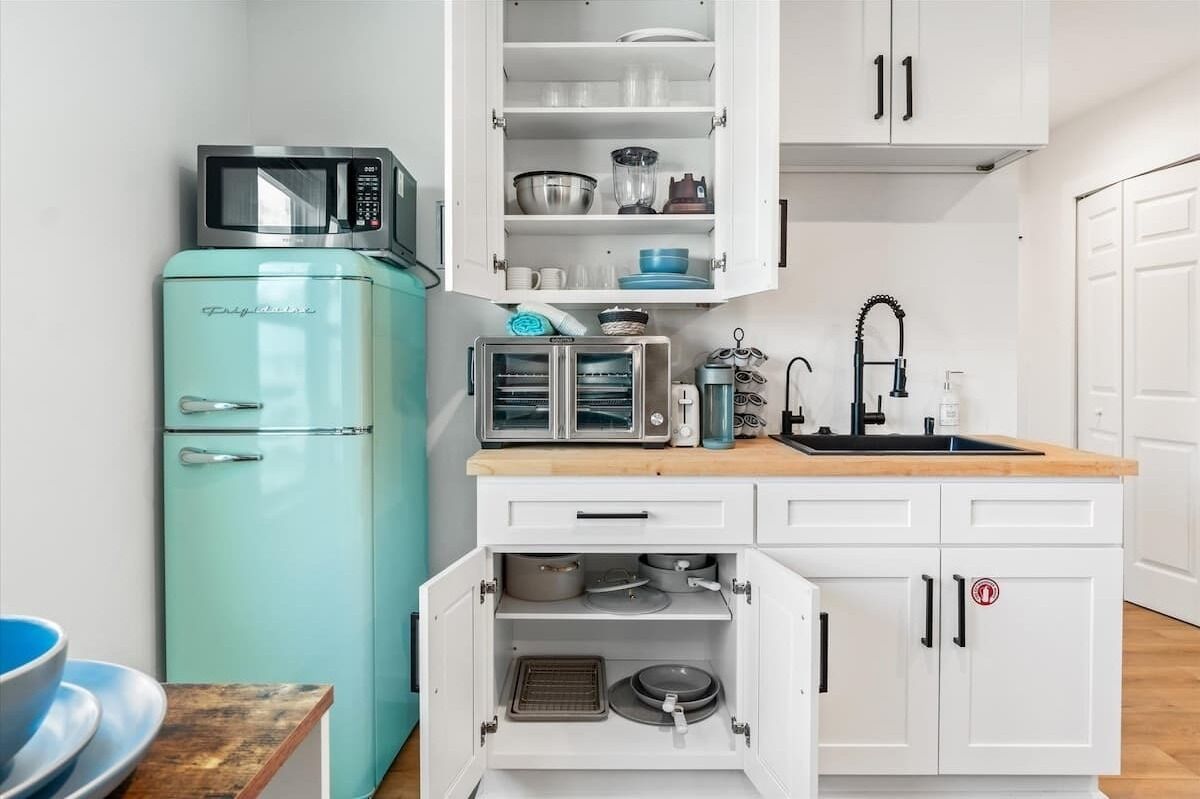 A compact kitchen with a teal refrigerator, a microwave, a toaster, and a sink.