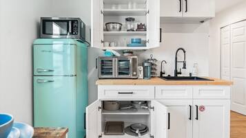 A compact kitchen with a teal refrigerator, a microwave, a toaster, and a sink.