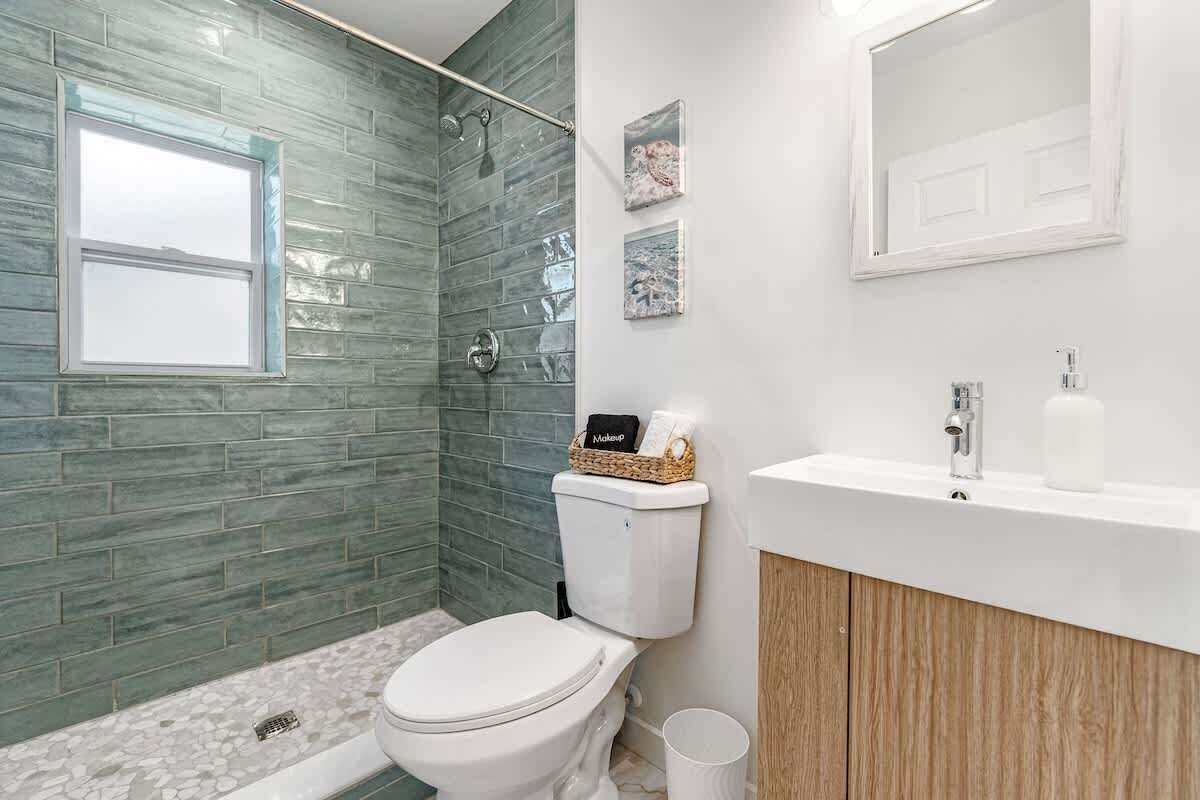 A bathroom with a shower, toilet, sink, and a window.