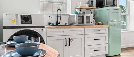 Eine moderne Küche mit weißen Schränken, einem grünen Kühlschrank, einer Mikrowelle und einem Toaster.