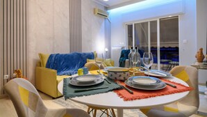 A dining area with a round table set for four, a sofa, and a view of the outdoors. - Serenity and 2 bedroom Luxury in Kalamaria (Kalamaria)