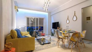 A modern living room with a sofa, coffee table, and dining area with chairs. - Serenity and 2 bedroom Luxury in Kalamaria (Kalamaria)