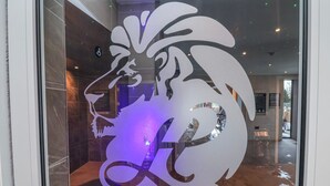Logotipo de cabeza de león en una puerta de cristal con el reflejo del interior de una habitación.