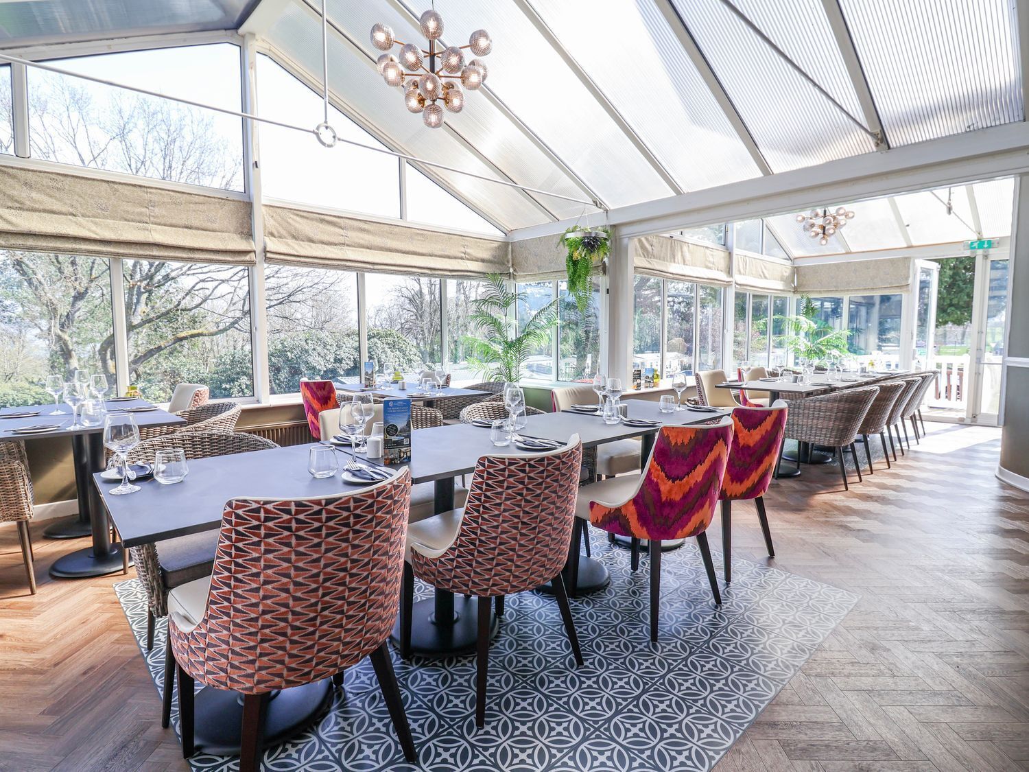 A restaurant with tables and chairs, large windows, and a patterned floor.