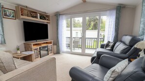 Una sala de estar con un televisor de pantalla plana, un sofá, una mesa de centro y un puerta corrediza de vidrio que da a un patio exterior.