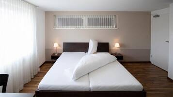 Ein Hotelzimmer mit Bett, zwei Nachttischen, einem Fenster mit Jalousien und einer Tür.