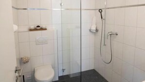 Un bagno moderno con cabina doccia in vetro, un WC e un lavandino.
