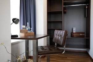 A room with a desk, chair, and a built-in closet with shelves.