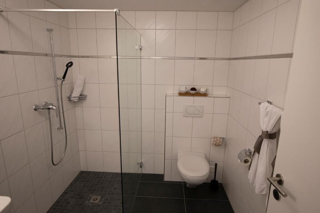 Um banheiro pequeno e moderno, com box de vidro, vaso sanitário e porta-toalhas.