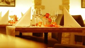 Una tavola imbandita con bicchieri da vino, una candela e una rosa.