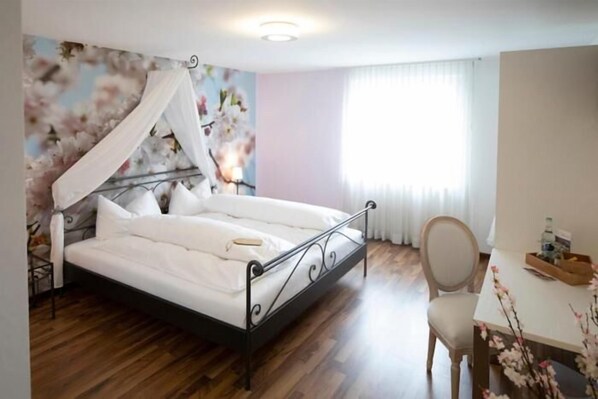 Un dormitorio con cama, escritorio, silla y ventana con cortinas.