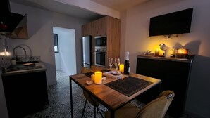 Eine moderne Küche mit Essbereich, ausgestattet mit einem Holztisch, Stühlen, einer Weinflasche, Gläsern und einer brennenden Kerze.