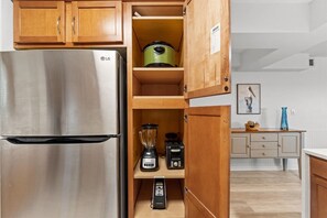A kitchen with a stainless steel refrigerator, a blender, and a toaster on a wooden shelf. - Gulffront Condo w/ Tiki Bar, Pools, & Sunsets (Panama City Beach)