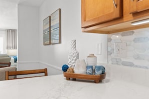 A kitchen with white cabinets, a marble countertop, and a hexagonal tile backsplash. - Gulffront Condo w/ Tiki Bar, Pools, & Sunsets (Panama City Beach)