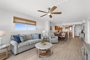 A modern living room with a sofa, coffee table, and a ceiling fan. - Gulffront Condo w/ Tiki Bar, Pools, & Sunsets (Panama City Beach)