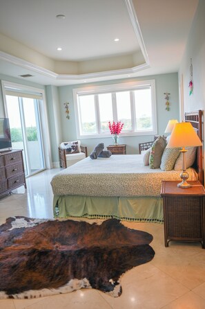 A spacious bedroom with a large bed, a television, a cowhide rug, and a window with a view. - Landmark 301  Ocean View 3BR Corner Residence w/ Large Private Balcony (Cozumel)