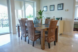 A dining area with wicker chairs, a wooden table, and a vase. - Landmark 301  Ocean View 3BR Corner Residence w/ Large Private Balcony (Cozumel)