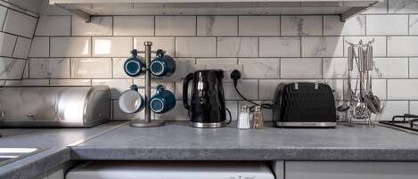 A kitchen with a built-in washing machine, a coffee maker, a toaster, and a kettle.