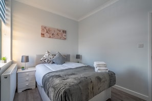A bedroom with a bed, bedside tables, a radiator, a wall art piece, and a window. - Modern Flat in Waterloo - Central London (London)