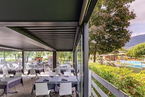 An outdoor dining area with tables and chairs, a pool, and a view of the surrounding landscape. - Mobile Home at Lake Caldonazzo (Pergine Valsugana)