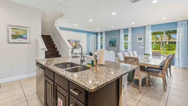 A modern kitchen with granite countertops, a built-in dishwasher, and a dining area with a glass table and chairs. - Where Family Vacations Feel Relaxed & Easy @ Emerald Palms Retreat Encore Resort (Kissimmee)