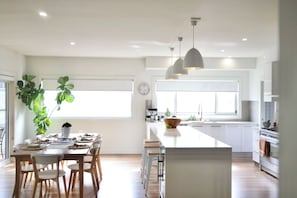 A modern kitchen with a central island, white cabinetry, and pendant lighting. - Alexander House - Pet Friendly - Winter (Robe)