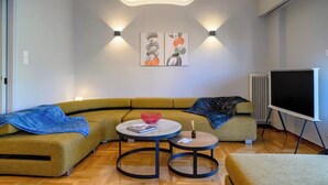 Una sala de estar moderna con un sofá seccional, dos mesas redondas, un televisor de pantalla plana e iluminación empotrada.