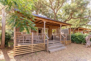 A wooden cabin with a porch, a staircase, and a covered seating area. - Mobilhome im Ferienpark mit Grosser Poolanlage (Castiglione della Pescaia)