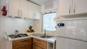 A modern kitchen with white cabinets, a stainless steel sink, and a built-in gas stove. - Mobilhome im Ferienpark mit Grosser Poolanlage (Castiglione della Pescaia)